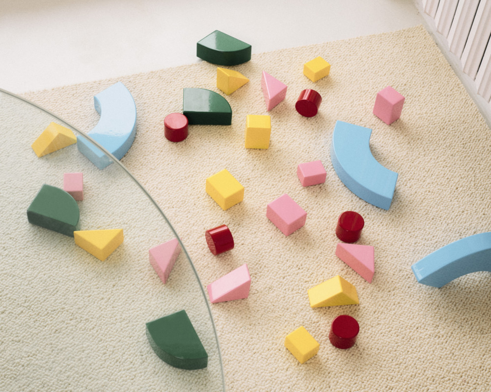Discrete elements drawn from the Little Family collection by nara.world arranged into a layered, sculptural composition on a glass table