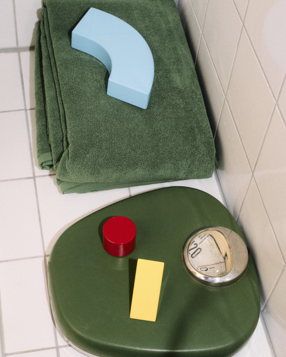 Playful units from the Little Family series by nara.world placed in a bathroom setting on a scale and towels