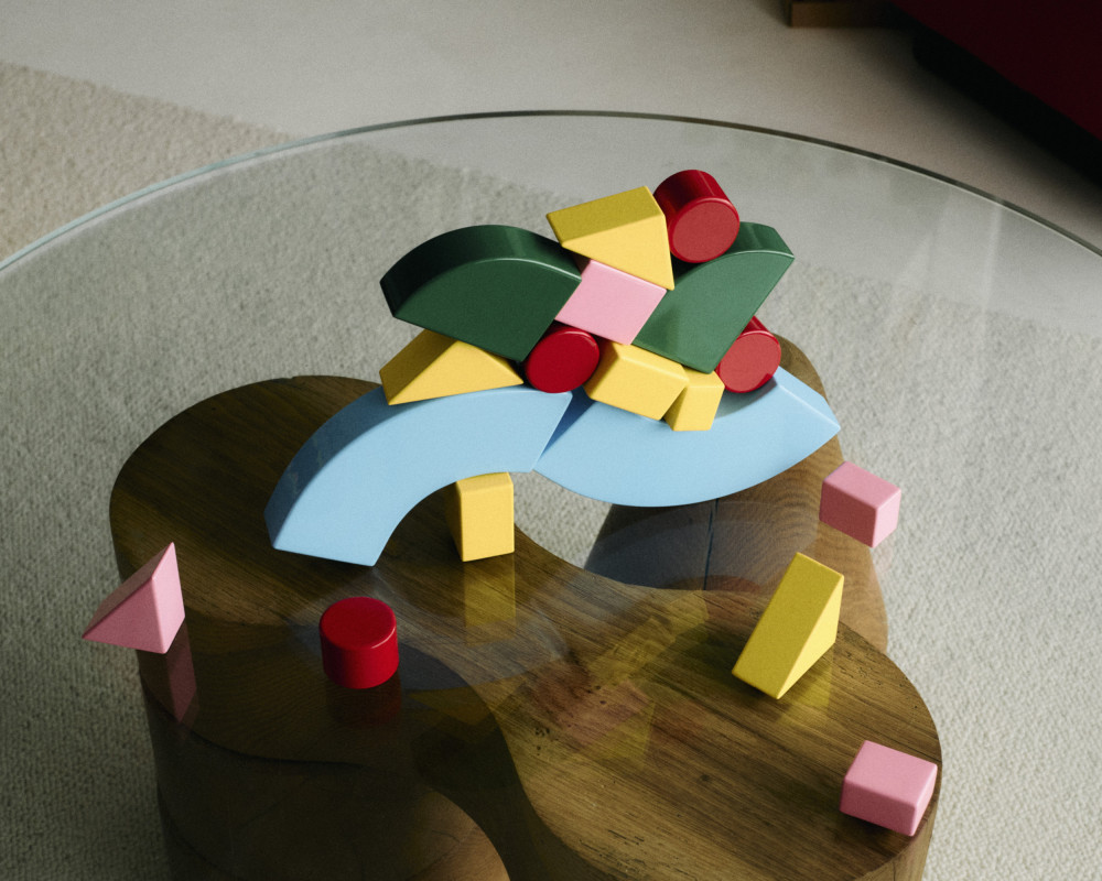 Colorful modular blocks from the Little Family collection by nara.world stacked and scattered on a glass table in a playful, unbalanced composition